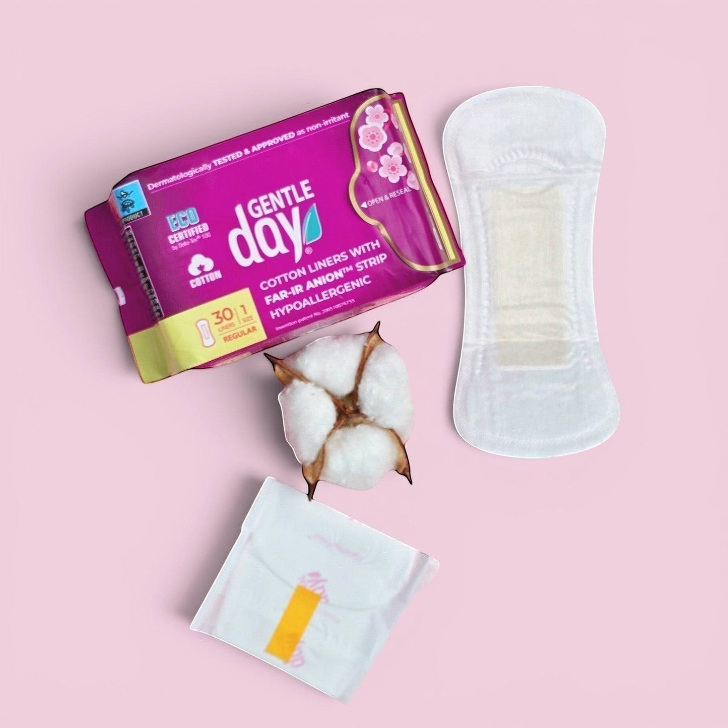 Gentle Day in South Africa organic cotton panty liners, individually wrapped and unwrapped, with cotton boll on pink background.