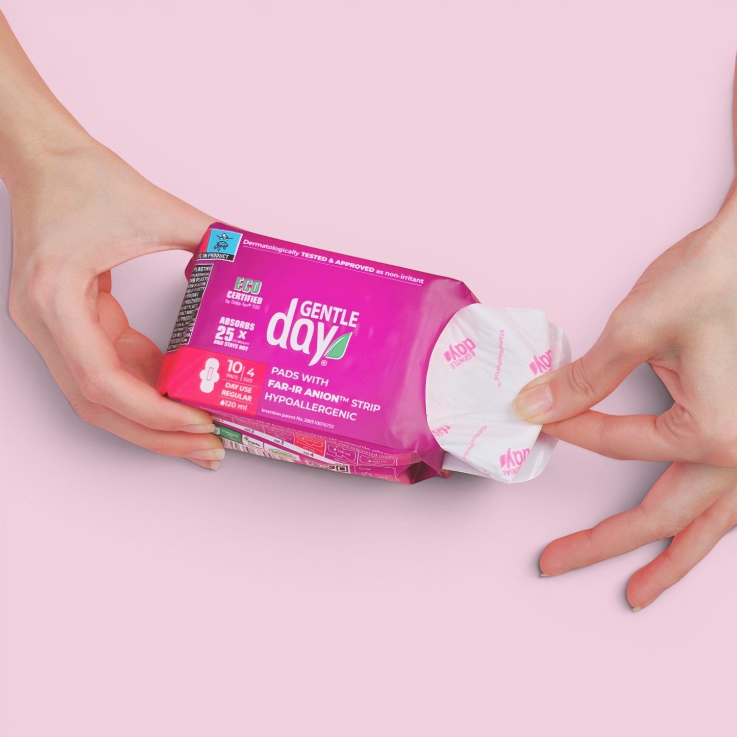 Hands opening a pack of Gentle Day in South Africa organic regular flow pads with wings on a soft pink background.